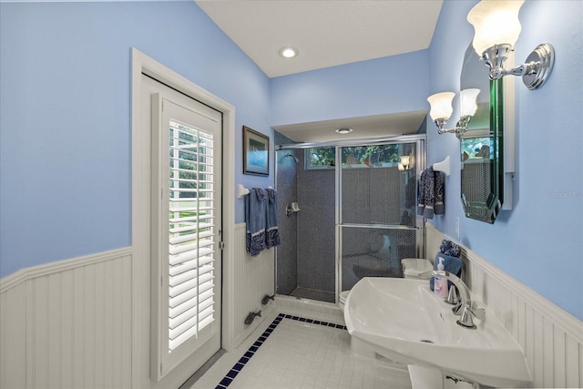 888 Royal Birkdale Dr, Tarpon Springs, FL 34688 - bathroom with a notable chandelier, a sink, tile patterned flooring, a wainscoted wall, and a stall shower