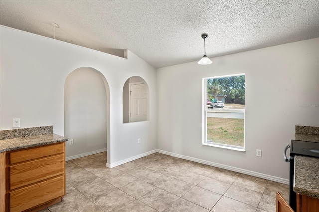 8461 Apple Orchard Rd, Spring Hill, FL 34608 - unfurnished dining area featuring light tile patterned floors, a textured ceiling, baseboards, and arched walkways
