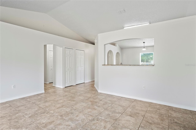 8461 Apple Orchard Rd, Spring Hill, FL 34608 - spare room with lofted ceiling, arched walkways, tile patterned floors, and baseboards