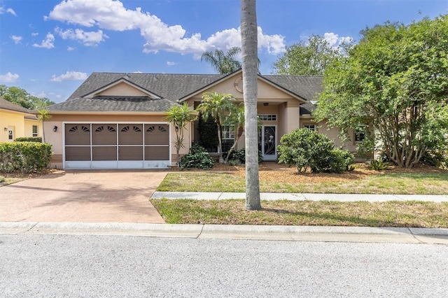 view of front of property with concrete driveway, stucco siding, roof with shingles, and a garage