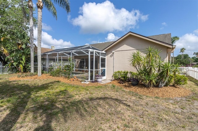 rear view of property with a fenced backyard, a lanai, and a lawn