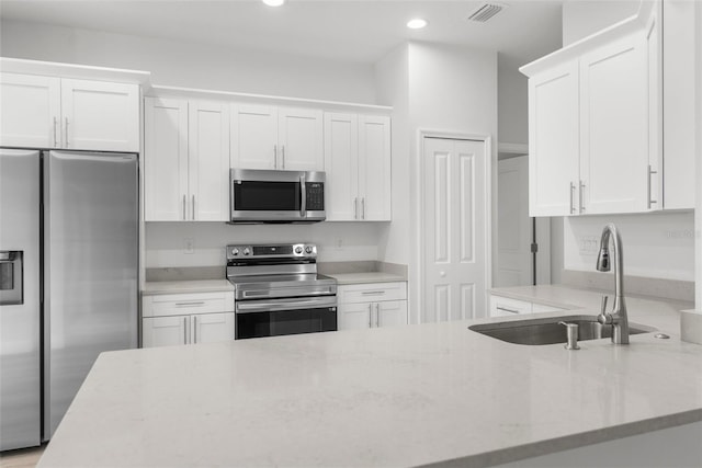 12331 Fulmar Rd, Weeki Wachee, FL 34614 - kitchen featuring appliances with stainless steel finishes, white cabinetry, light stone countertops, and recessed lighting