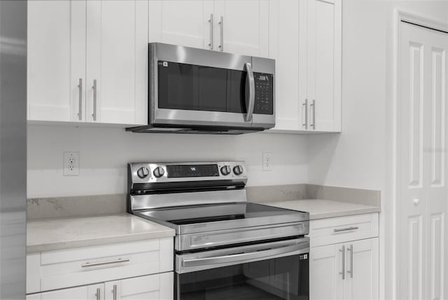 12331 Fulmar Rd, Weeki Wachee, FL 34614 - kitchen with stainless steel appliances, white cabinetry, and light stone countertops