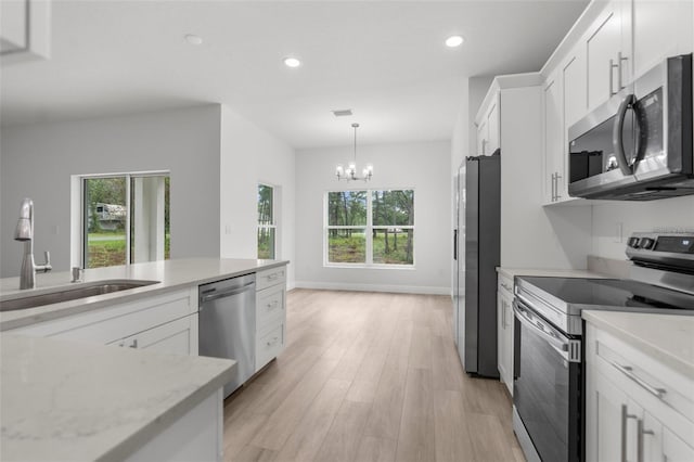 12331 Fulmar Rd, Weeki Wachee, FL 34614 - kitchen featuring stainless steel appliances, a chandelier, white cabinets, plenty of natural light, and recessed lighting