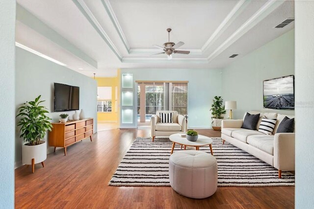 4080 Gevalia Dr, Brooksville, FL 34604 - living room featuring a ceiling fan, wood finished floors, a tray ceiling, visible vents, and ornamental molding