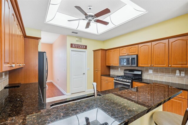 4080 Gevalia Dr, Brooksville, FL 34604 - kitchen with ceiling fan, decorative backsplash, appliances with stainless steel finishes, a sink, and dark stone countertops