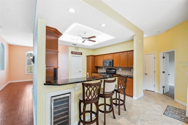 4080 Gevalia Dr, Brooksville, FL 34604 - kitchen featuring a breakfast bar, beverage cooler, stainless steel microwave, backsplash, and range