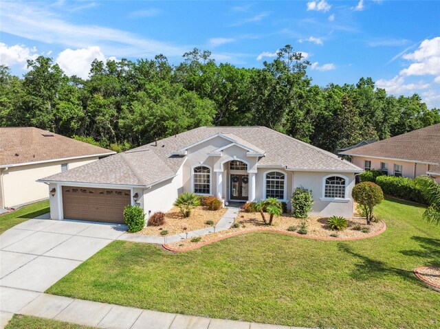 4080 Gevalia Dr, Brooksville, FL 34604 - view of front of property featuring french doors, a front yard, a garage, concrete driveway, and stucco siding