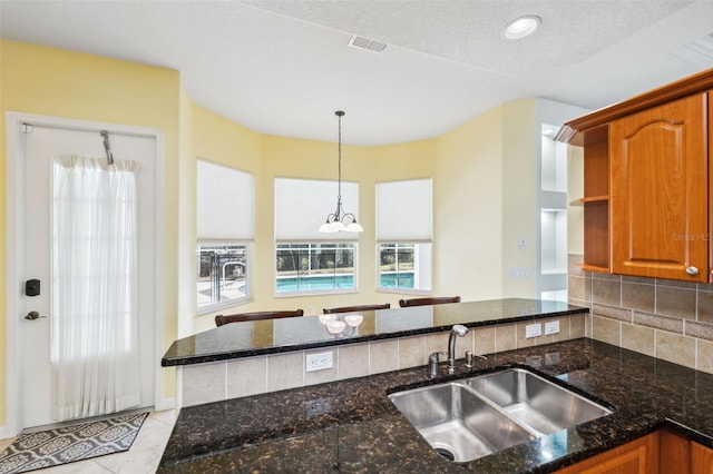 4080 Gevalia Dr, Brooksville, FL 34604 - kitchen featuring a sink, brown cabinetry, dark stone countertops, decorative light fixtures, and visible vents