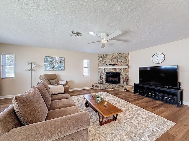 living area with a textured ceiling, ceiling fan, visible vents, and baseboards