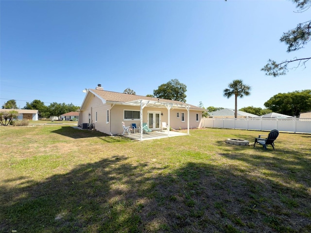 rear view of house with a chimney, french doors, fence, an outdoor fire pit, and a yard