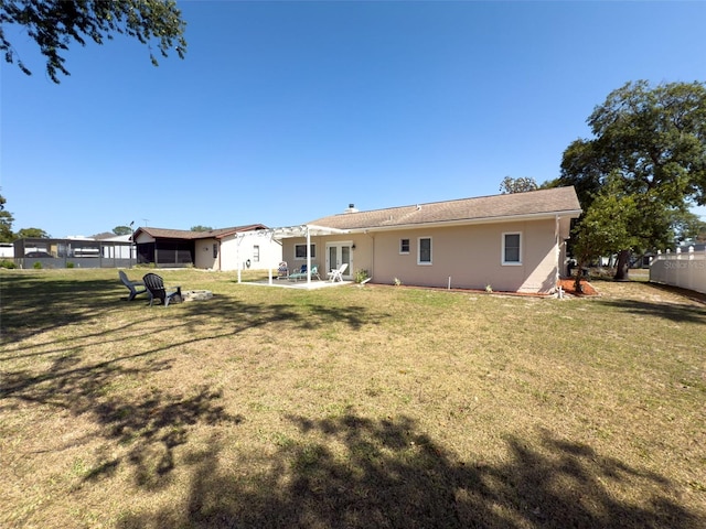 rear view of house with a lawn, stucco siding, and a patio area