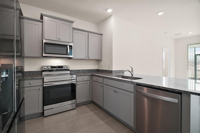 4106 NW 44th Cir, Ocala, FL 34482 - kitchen with gray cabinets, tile patterned floors, a sink, dark stone countertops, and appliances with stainless steel finishes