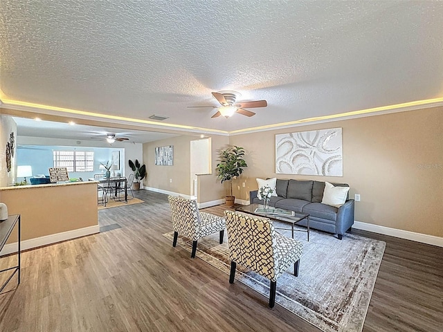 living area with visible vents, a ceiling fan, baseboards, and wood finished floors