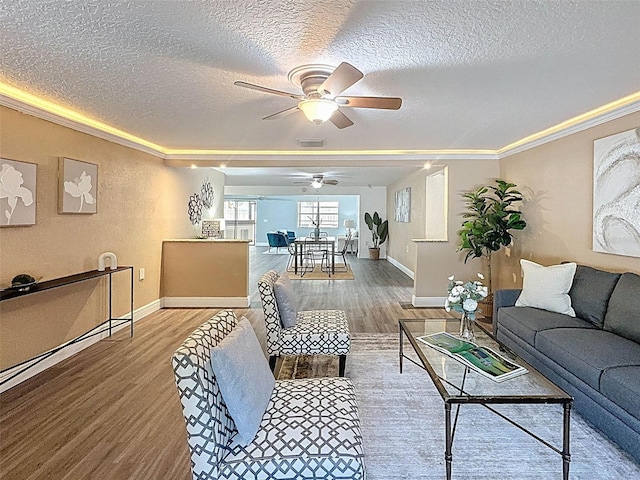 living area with crown molding, a textured ceiling, wood finished floors, and visible vents