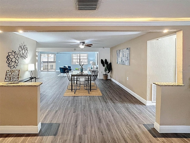 dining area featuring ceiling fan, a textured ceiling, visible vents, wood finished floors, and baseboards