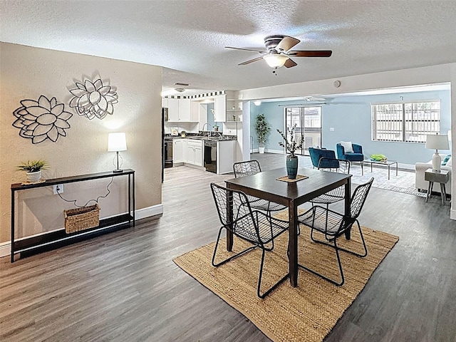 dining space with a textured wall, wood finished floors, baseboards, a textured ceiling, and a ceiling fan