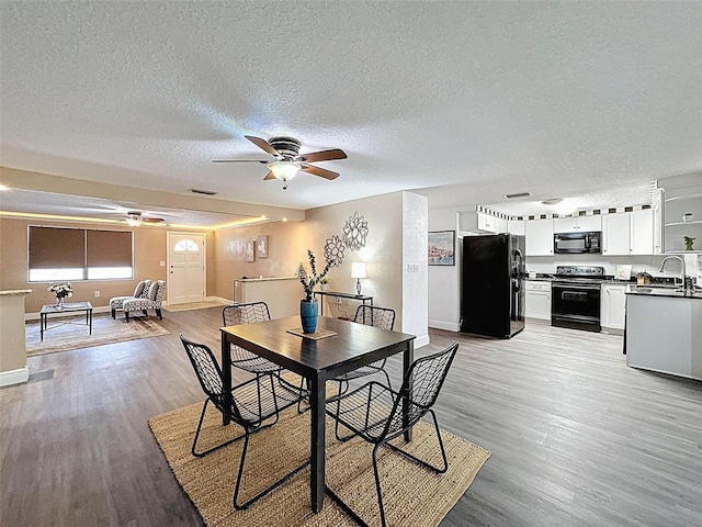 dining space featuring a ceiling fan, a textured ceiling, baseboards, and light wood-type flooring