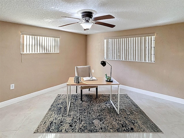 home office with a textured ceiling, ceiling fan, and baseboards