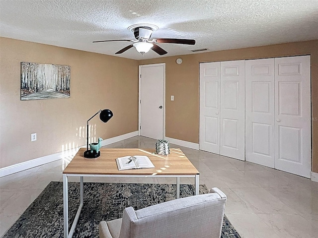 office featuring baseboards, a ceiling fan, a textured ceiling, and visible vents