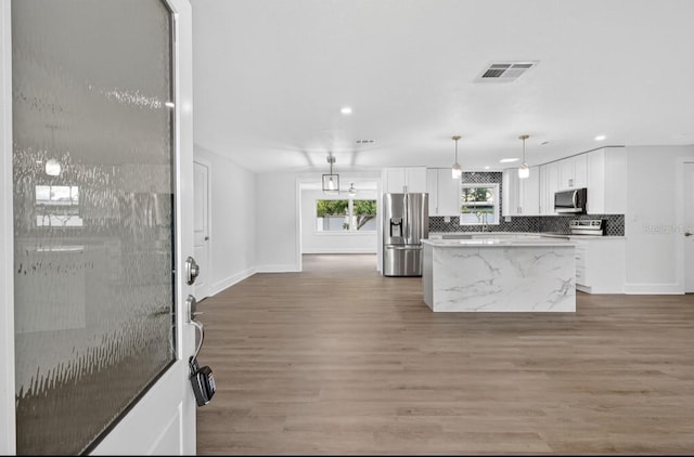2175 Edythe Dr, Dunedin, FL 34698 - kitchen featuring appliances with stainless steel finishes, a kitchen island, white cabinetry, light wood finished floors, and recessed lighting