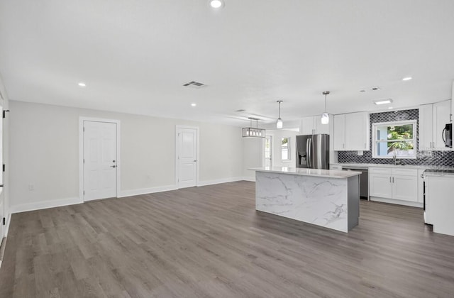 2175 Edythe Dr, Dunedin, FL 34698 - kitchen featuring stainless steel appliances, a kitchen island, tasteful backsplash, wood finished floors, and white cabinetry