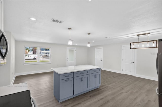 2175 Edythe Dr, Dunedin, FL 34698 - kitchen with gray cabinetry, wood finished floors, hanging light fixtures, light stone counters, and recessed lighting