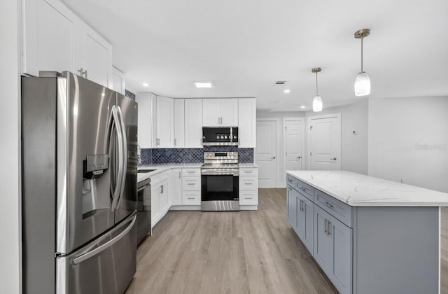 2175 Edythe Dr, Dunedin, FL 34698 - kitchen featuring appliances with stainless steel finishes, white cabinets, backsplash, light wood-style floors, and light stone counters