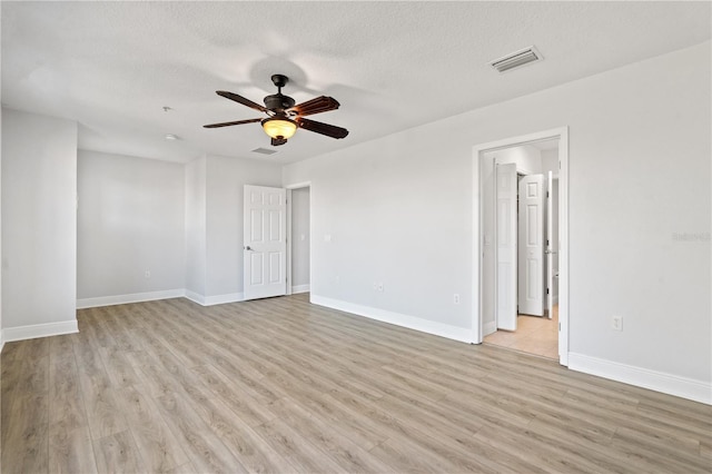 unfurnished room with baseboards, a ceiling fan, light wood finished floors, and visible vents
