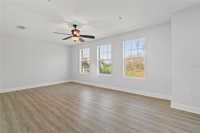 empty room featuring ceiling fan, visible vents, baseboards, and light wood-style floors