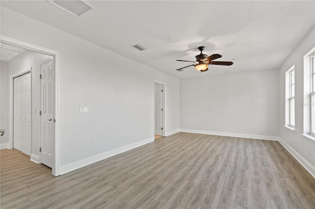 spare room with a ceiling fan, light wood-type flooring, and visible vents