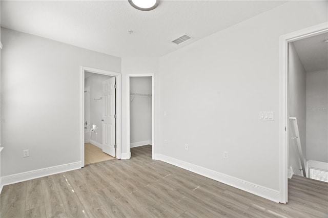 unfurnished bedroom featuring baseboards, wood finished floors, and visible vents