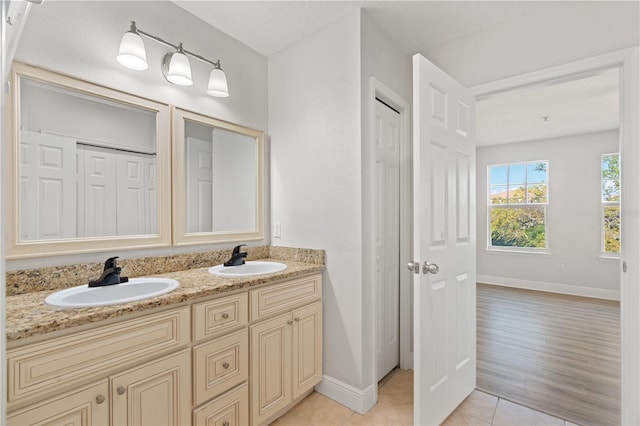 full bathroom with double vanity, a sink, baseboards, and tile patterned floors