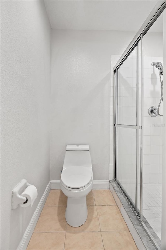 bathroom with baseboards, a stall shower, and toilet