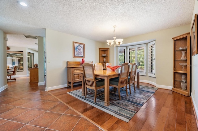 663 Turnberry Ct, Tarpon Springs, FL 34688 - dining space with dark wood-style flooring, a textured ceiling, a chandelier, baseboards, and visible vents