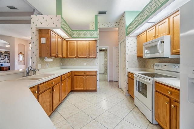 kitchen with a sink, light countertops, white appliances, and visible vents