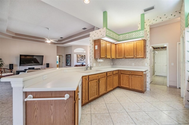 kitchen featuring light tile patterned flooring, ceiling fan, a sink, light countertops, and a peninsula