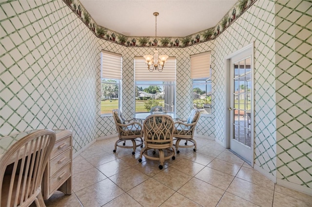 dining area with light tile patterned floors, wallpapered walls, an inviting chandelier, and a healthy amount of sunlight