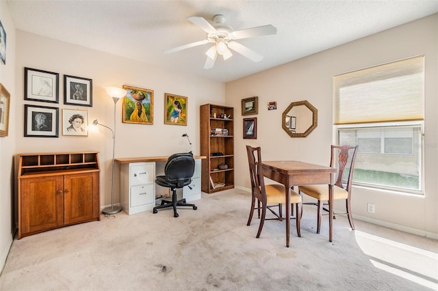 office featuring a ceiling fan, baseboards, light carpet, and plenty of natural light
