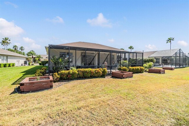 back of property featuring a lawn, a garden, and a lanai