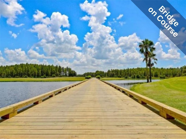 view of dock featuring a yard, a water view, and a view of trees