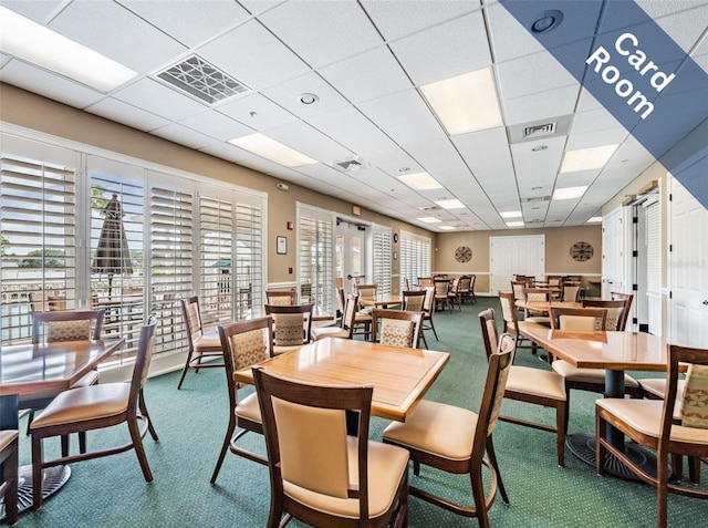 carpeted dining room featuring plenty of natural light, a drop ceiling, and visible vents