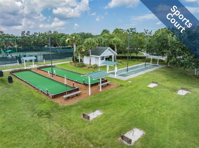 surrounding community with a lawn, fence, and shuffleboard