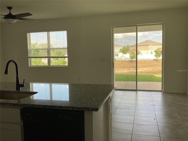 12630 Aston Dr, Hudson, FL 34669 - kitchen featuring a ceiling fan, a sink, light tile patterned floors, dark stone countertops, and black dishwasher