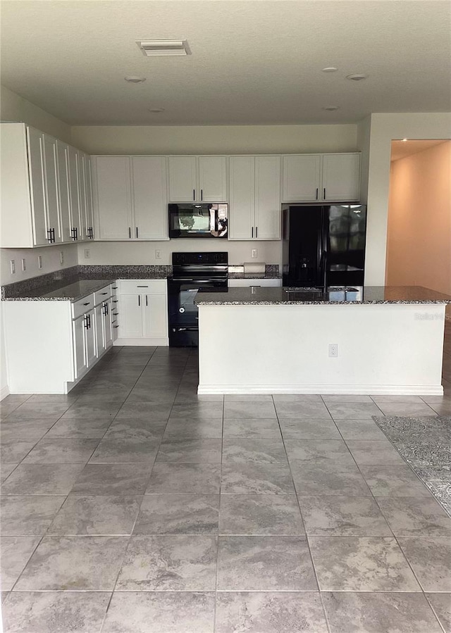 12630 Aston Dr, Hudson, FL 34669 - kitchen with visible vents, a kitchen island, white cabinets, dark stone countertops, and black appliances