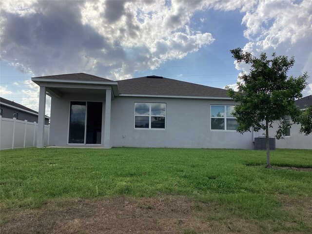 12630 Aston Dr, Hudson, FL 34669 - back of house with roof with shingles, stucco siding, a yard, and fence