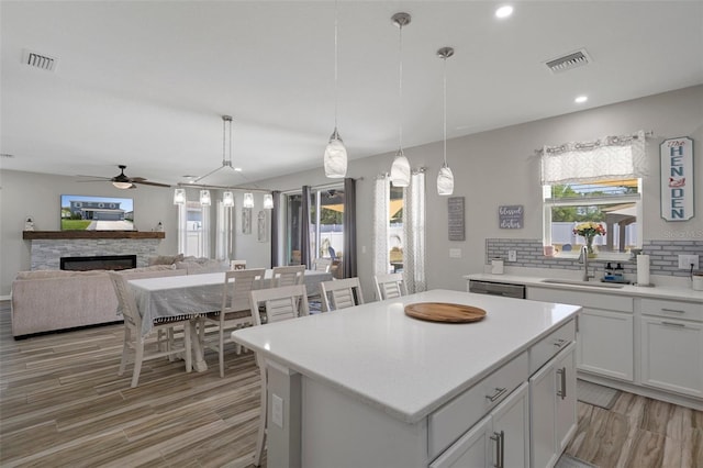 733 Old Windsor Way, Spring Hill, FL 34609 - kitchen featuring light wood-style floors, ceiling fan, a warm lit fireplace, plenty of natural light, and a sink