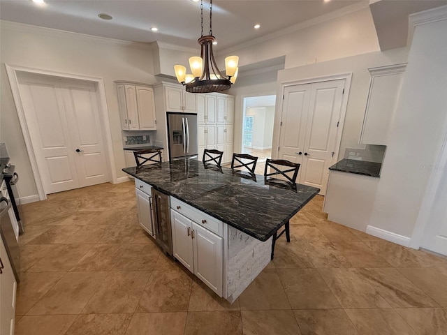 210 S Hale Ave, Tampa, FL 33609 - kitchen featuring stainless steel refrigerator with ice dispenser, a kitchen bar, ornamental molding, a center island, and baseboards