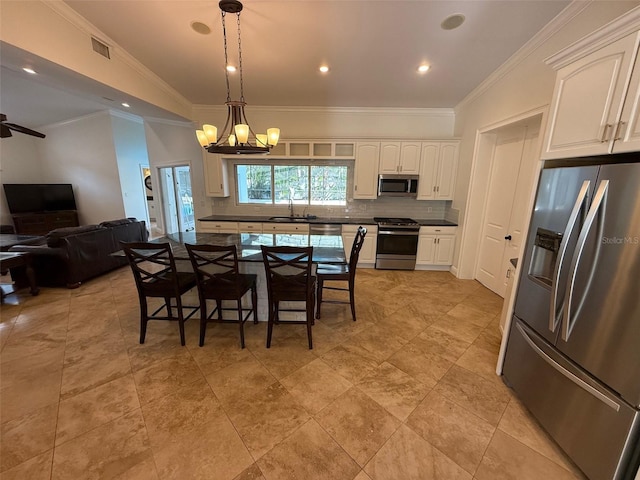 210 S Hale Ave, Tampa, FL 33609 - kitchen featuring stainless steel appliances, a sink, backsplash, white cabinetry, and crown molding