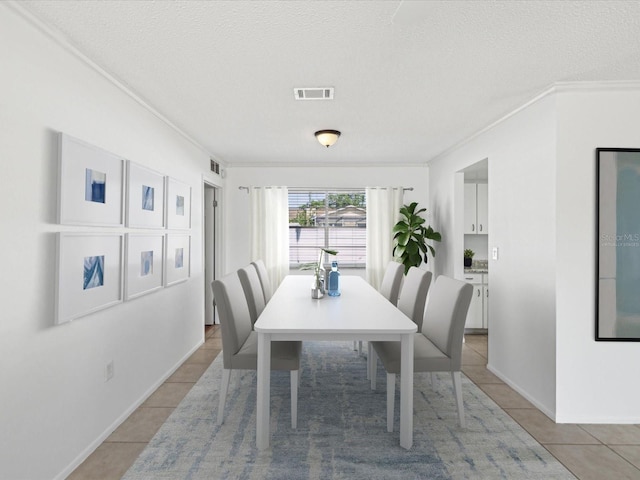dining room with visible vents, a textured ceiling, crown molding, and light tile patterned floors
